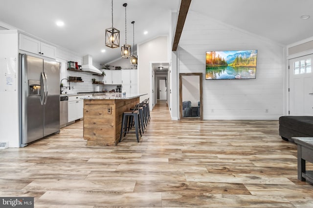 kitchen with light wood-style floors, a breakfast bar area, stainless steel appliances, and open floor plan