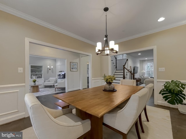 dining area featuring stairway, a wainscoted wall, crown molding, a decorative wall, and light wood-type flooring