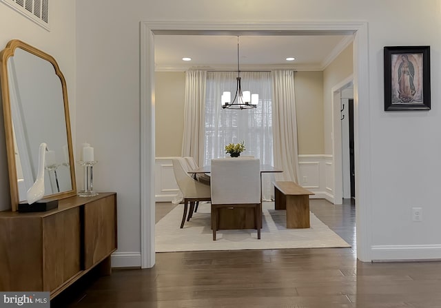 dining room with visible vents, dark wood finished floors, ornamental molding, an inviting chandelier, and a decorative wall