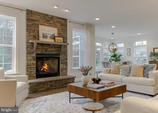 living room with recessed lighting, a stone fireplace, wood finished floors, and an inviting chandelier