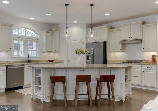 kitchen featuring under cabinet range hood, open shelves, a kitchen breakfast bar, a center island, and stainless steel appliances