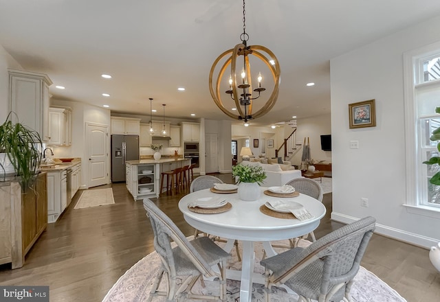 dining space with stairway, wood finished floors, baseboards, recessed lighting, and a notable chandelier