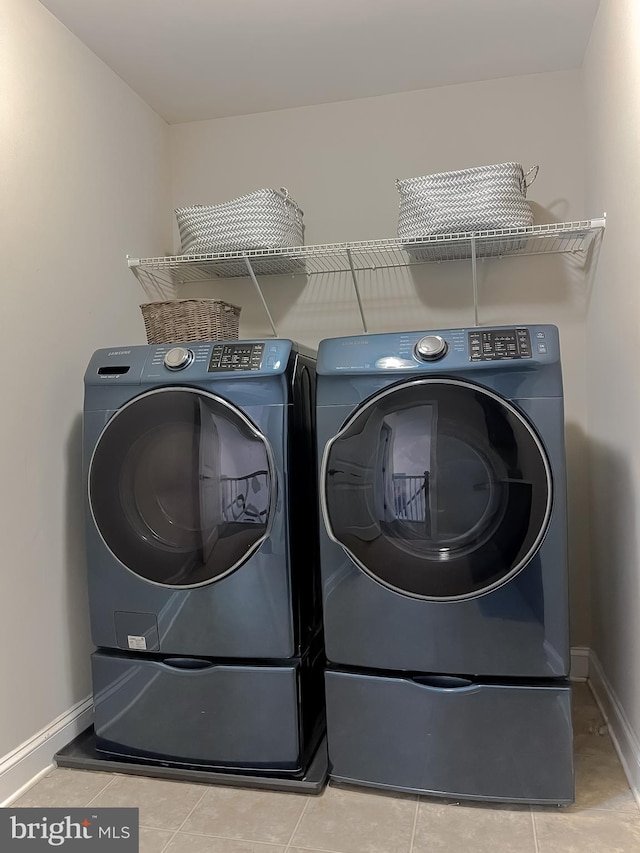 laundry area with light tile patterned floors, baseboards, independent washer and dryer, and laundry area