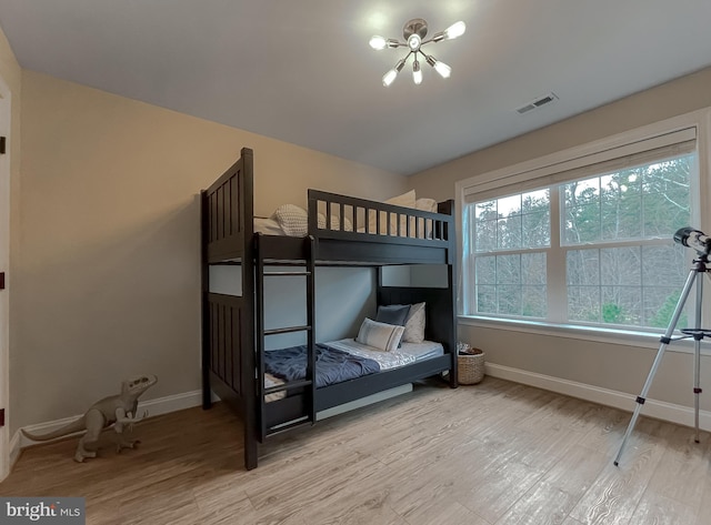 bedroom featuring a notable chandelier, wood finished floors, visible vents, and baseboards