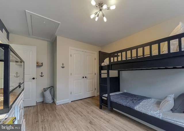 bedroom with attic access, baseboards, a closet, and light wood finished floors