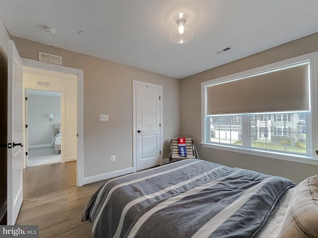 bedroom with wood finished floors, visible vents, and baseboards