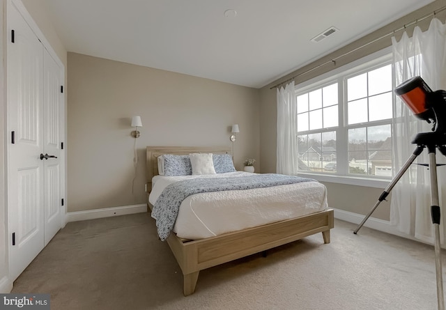 bedroom with visible vents, light colored carpet, and baseboards