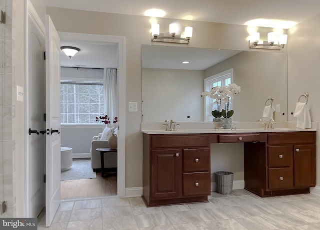 full bath featuring a sink, baseboards, and double vanity