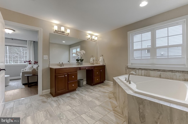 full bath with double vanity, a garden tub, baseboards, and a sink