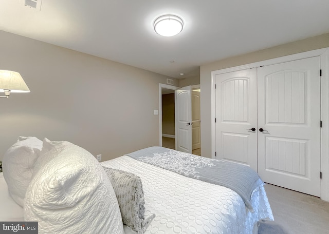 bedroom featuring visible vents, a closet, and light carpet