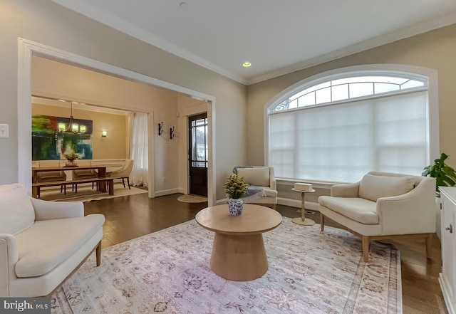 living area featuring baseboards, wood finished floors, an inviting chandelier, and ornamental molding