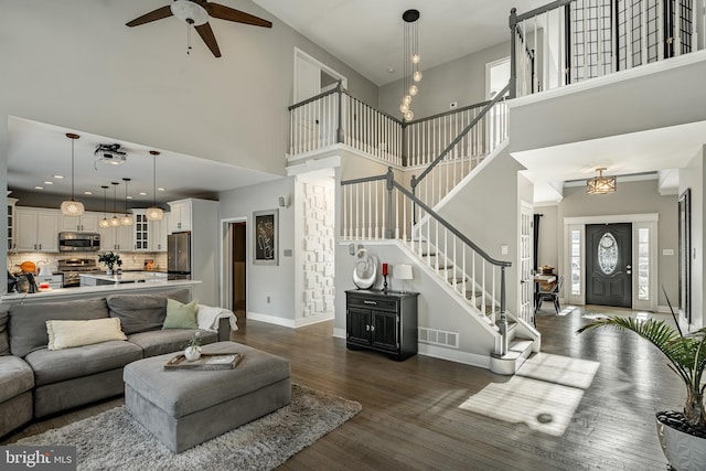 living room featuring a wealth of natural light, visible vents, dark wood finished floors, and stairs