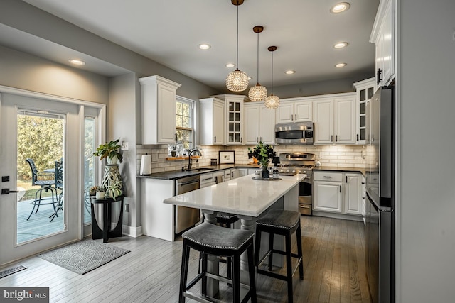 kitchen with a kitchen island, appliances with stainless steel finishes, dark wood-style floors, white cabinetry, and a sink