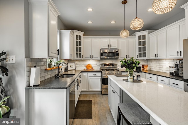 kitchen with a sink, stainless steel appliances, white cabinets, and light wood finished floors