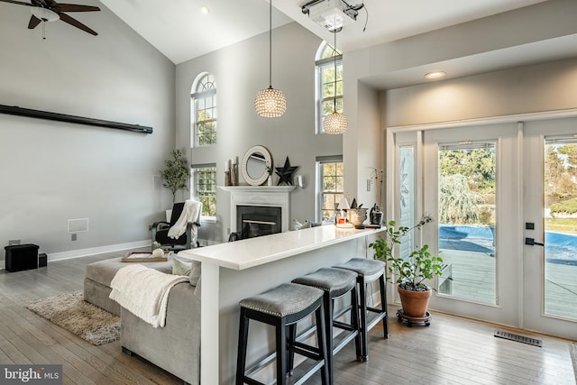 living room featuring a glass covered fireplace, hardwood / wood-style flooring, visible vents, and high vaulted ceiling