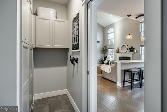 hallway with dark wood finished floors, a high ceiling, and baseboards