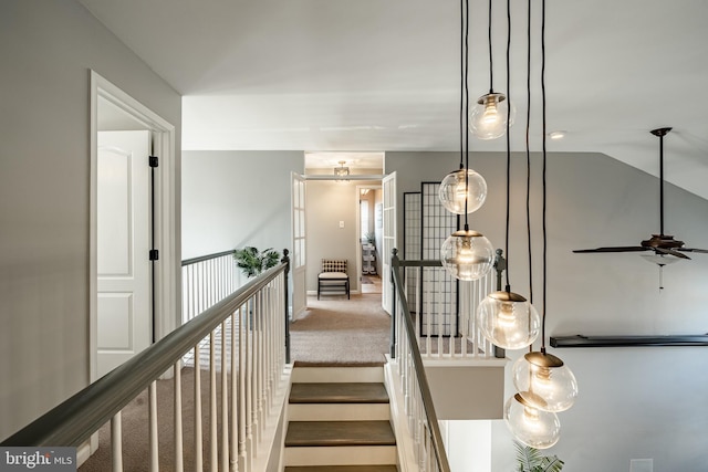 hall featuring vaulted ceiling, carpet flooring, and an upstairs landing