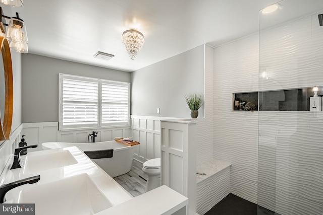 bathroom with wainscoting, a freestanding tub, walk in shower, and a sink