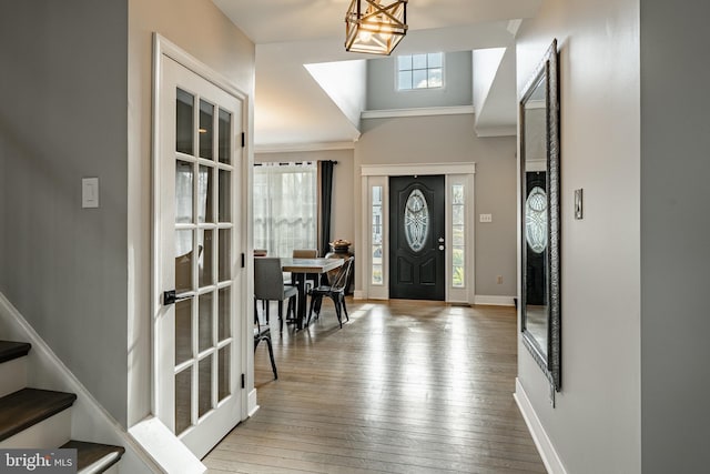 entrance foyer featuring crown molding, stairs, baseboards, and hardwood / wood-style floors