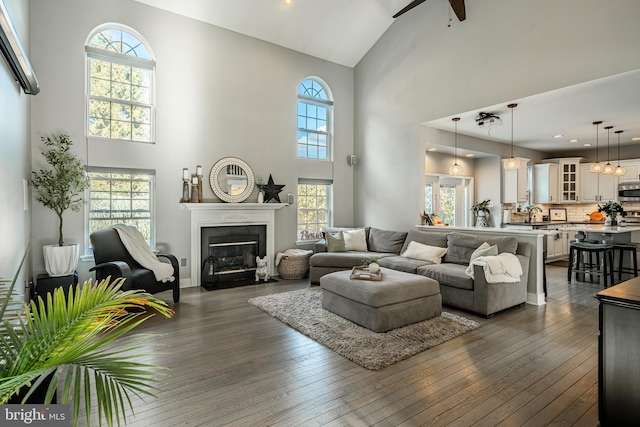 living room featuring dark wood-type flooring, a fireplace with flush hearth, plenty of natural light, and ceiling fan