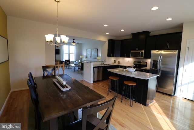 dining room featuring recessed lighting, an inviting chandelier, light wood-type flooring, and baseboards