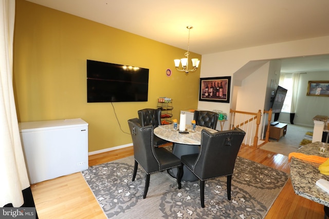 dining room with a notable chandelier, baseboards, and wood finished floors