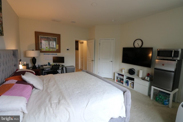 carpeted bedroom with freestanding refrigerator