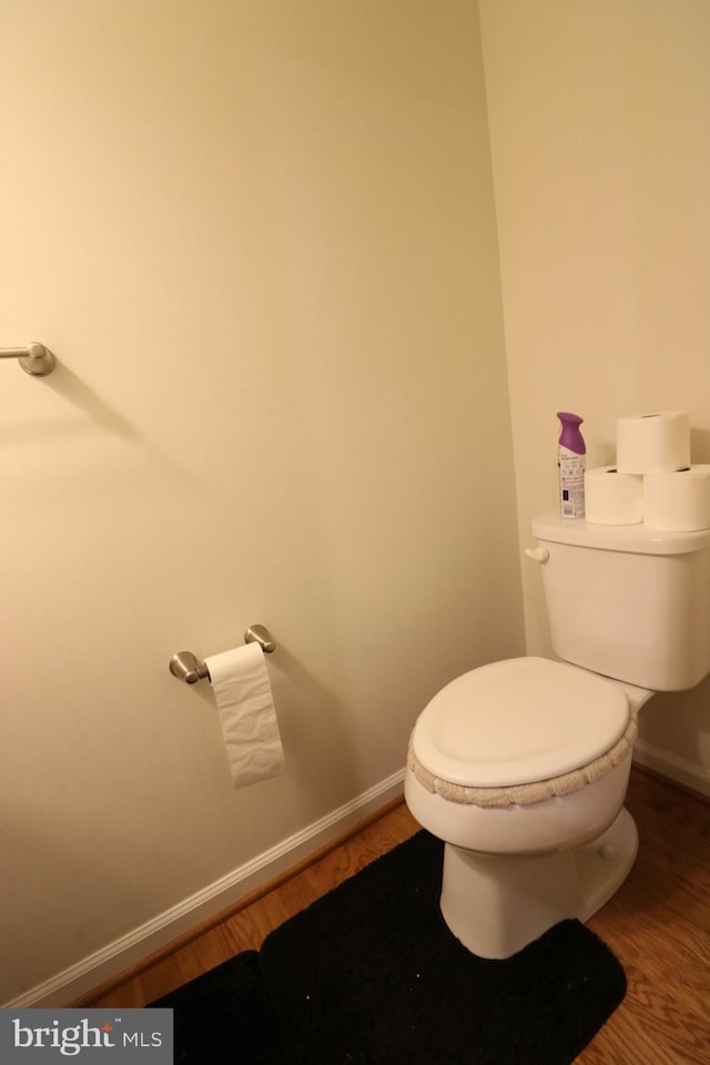 bathroom with toilet, baseboards, and wood finished floors