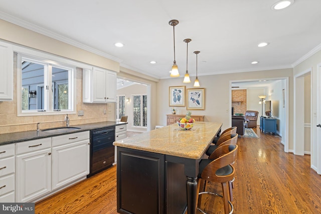 kitchen featuring black dishwasher, a breakfast bar, wood finished floors, and white cabinets