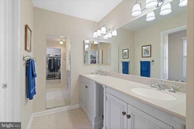 full bath with a sink, a walk in closet, double vanity, and tile patterned flooring