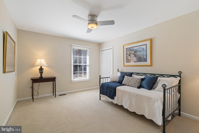 bedroom featuring a closet, light colored carpet, baseboards, and ceiling fan