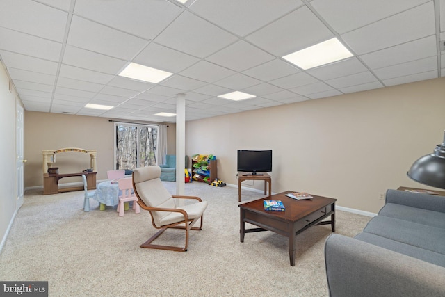 carpeted living room with baseboards and a drop ceiling