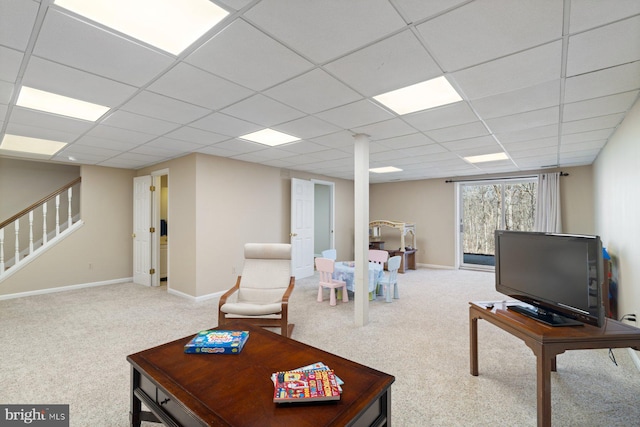 carpeted living area featuring stairs, baseboards, and a drop ceiling