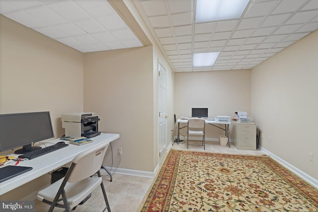 office area featuring tile patterned floors, a paneled ceiling, and baseboards