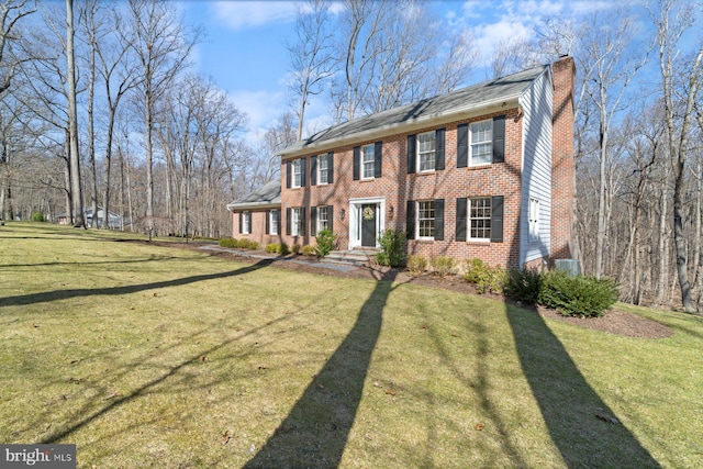 colonial inspired home with a front lawn, brick siding, central AC unit, and a chimney