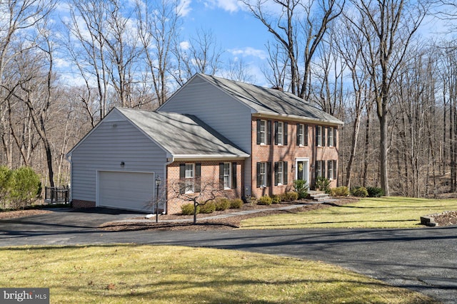 view of front of home featuring brick siding, driveway, a front lawn, and a garage