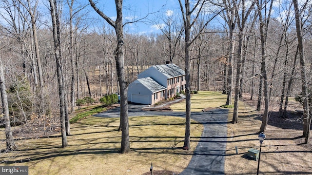 view of front of home featuring a wooded view and a front lawn