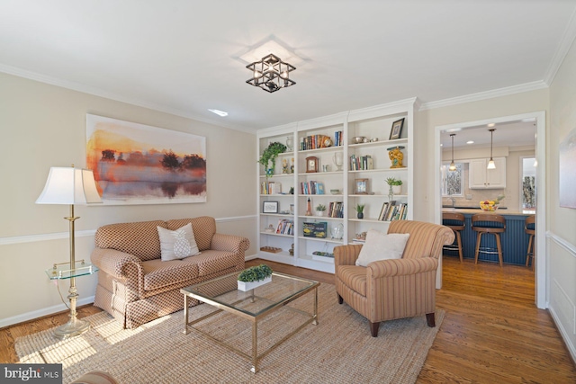 sitting room featuring baseboards, wood finished floors, and ornamental molding