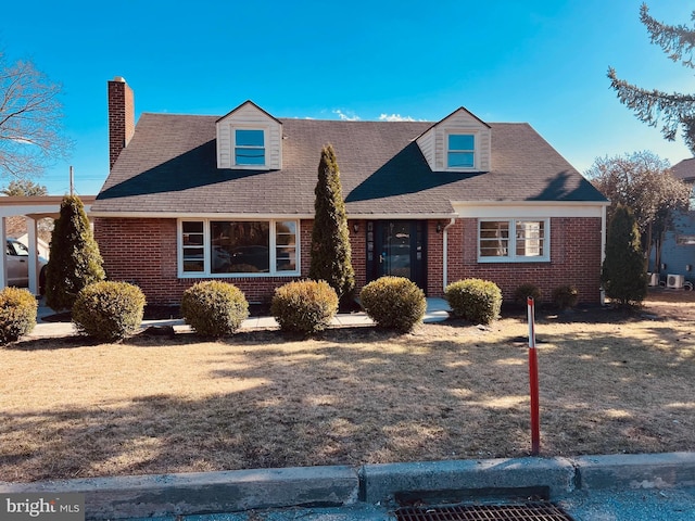 cape cod-style house with brick siding, a chimney, and a front yard