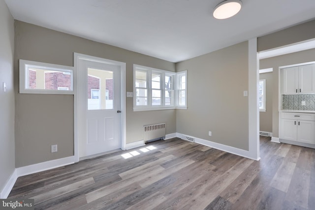 entryway with baseboards, radiator, and wood finished floors