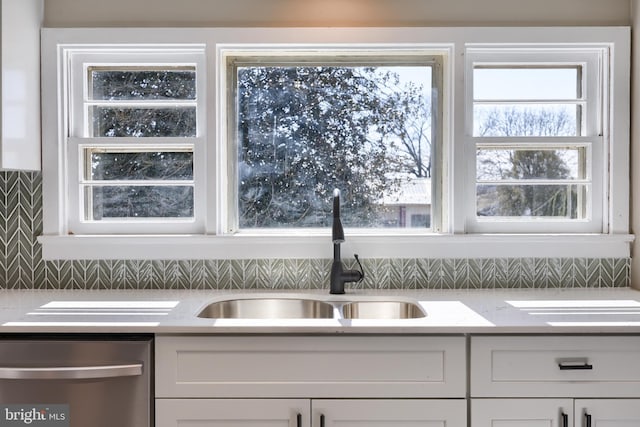 kitchen featuring white cabinets, dishwasher, light countertops, and a sink