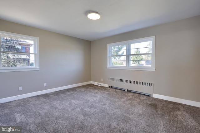 carpeted spare room with baseboards, plenty of natural light, and radiator heating unit