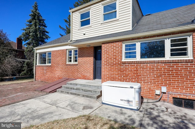 rear view of house with brick siding and roof with shingles