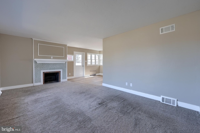 unfurnished living room with visible vents, a fireplace, baseboards, and carpet floors