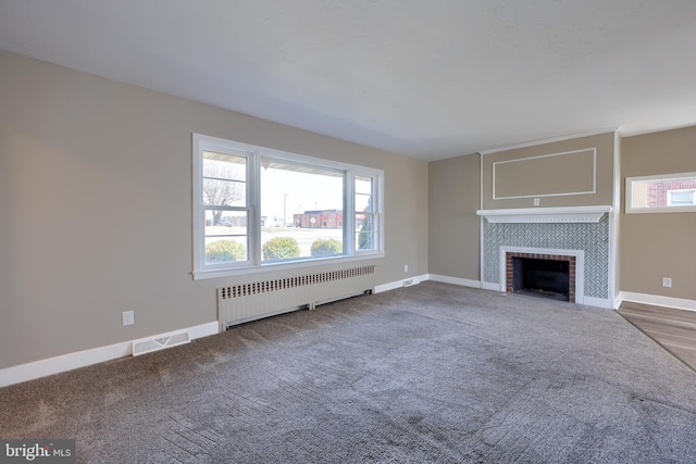 unfurnished living room with visible vents, radiator, carpet flooring, baseboards, and a tile fireplace