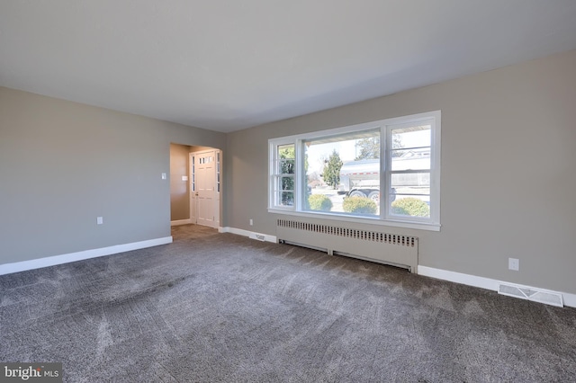 carpeted spare room with visible vents, radiator, and baseboards