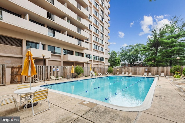 community pool with a patio area and fence