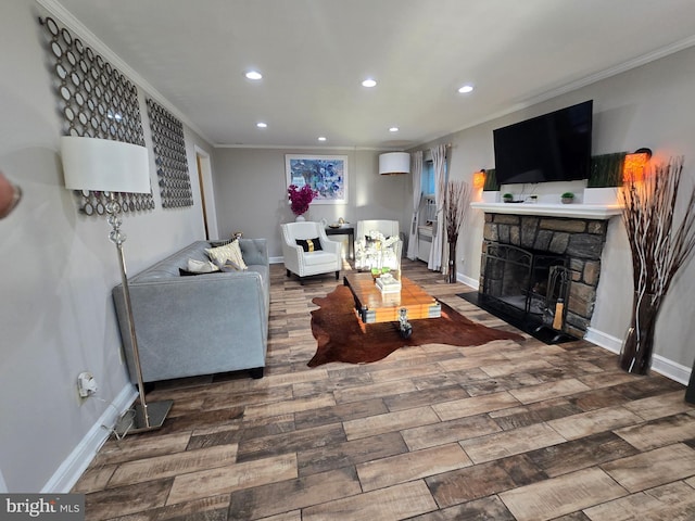 living room featuring recessed lighting, ornamental molding, a stone fireplace, wood finished floors, and baseboards