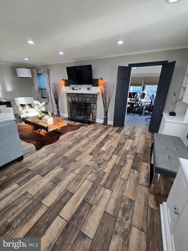 living room featuring baseboards, a fireplace, ornamental molding, and wood finished floors