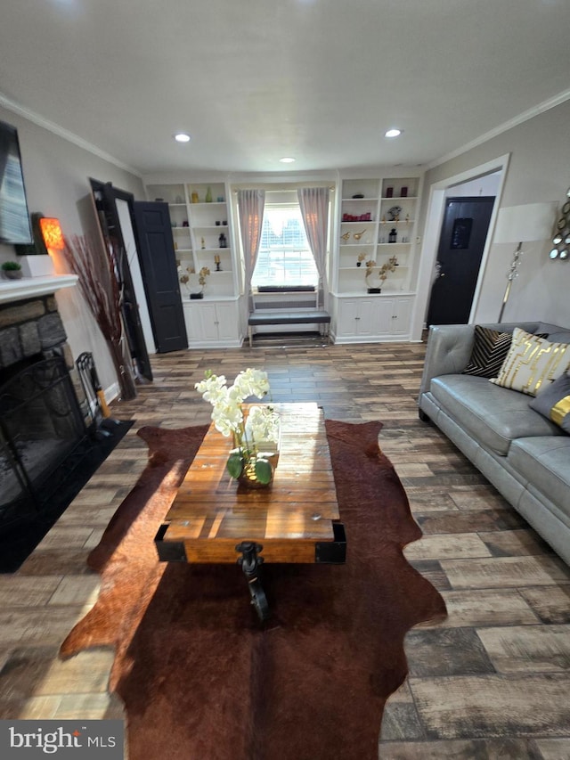 living area featuring a stone fireplace, ornamental molding, built in shelves, and recessed lighting